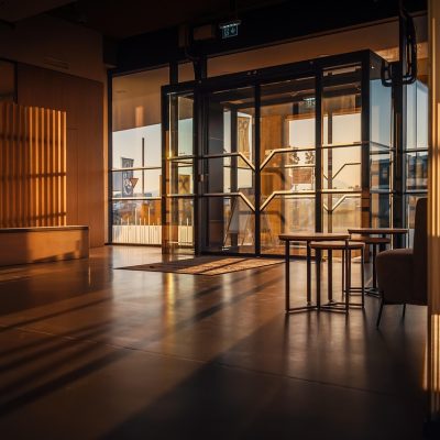 一位女性编辑在明亮的办公室里整理本地出行提示文档，桌边放着保温杯和记事本，窗外是城市楼群